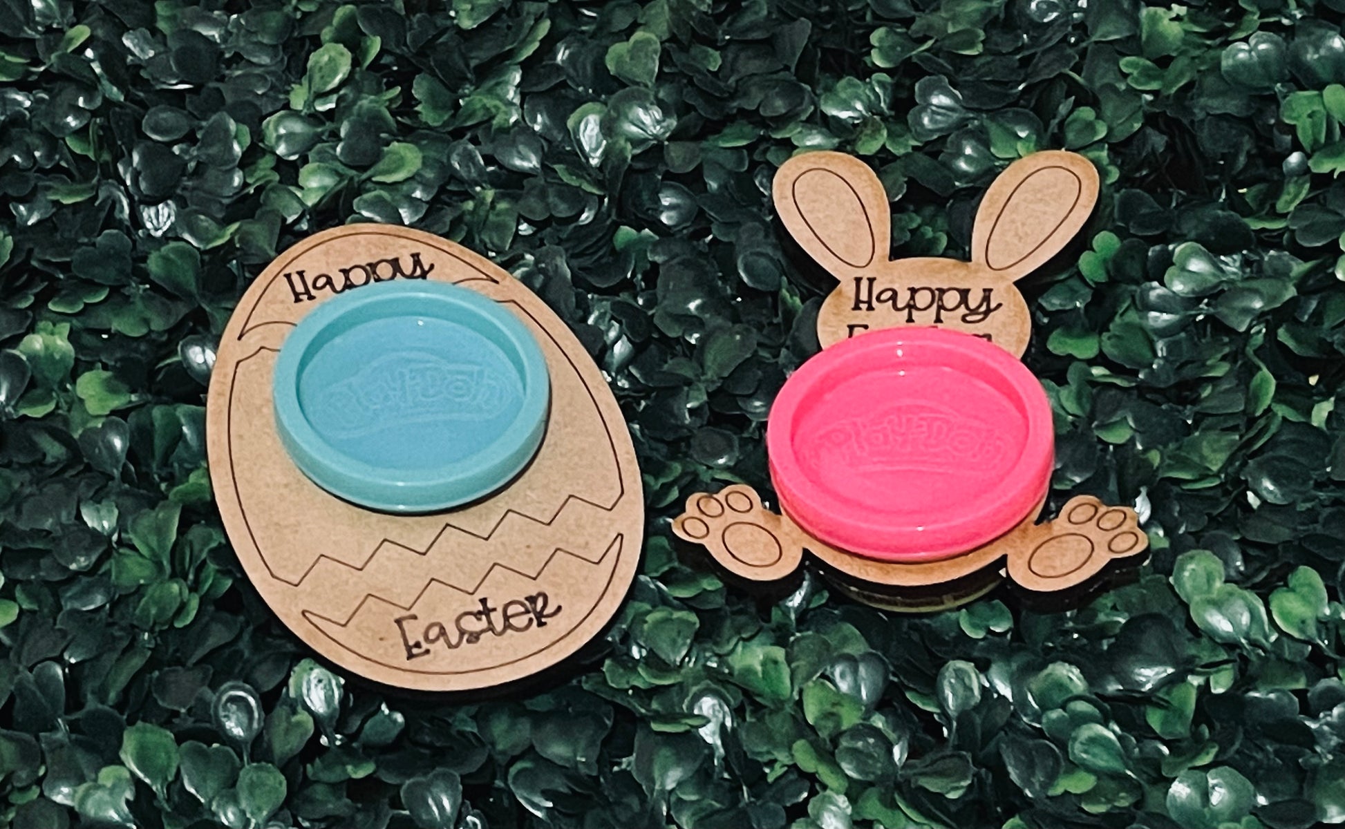 Two wood cutout playdoh container holders shaped like an Easter Egg and a bunny on a green leafy background.