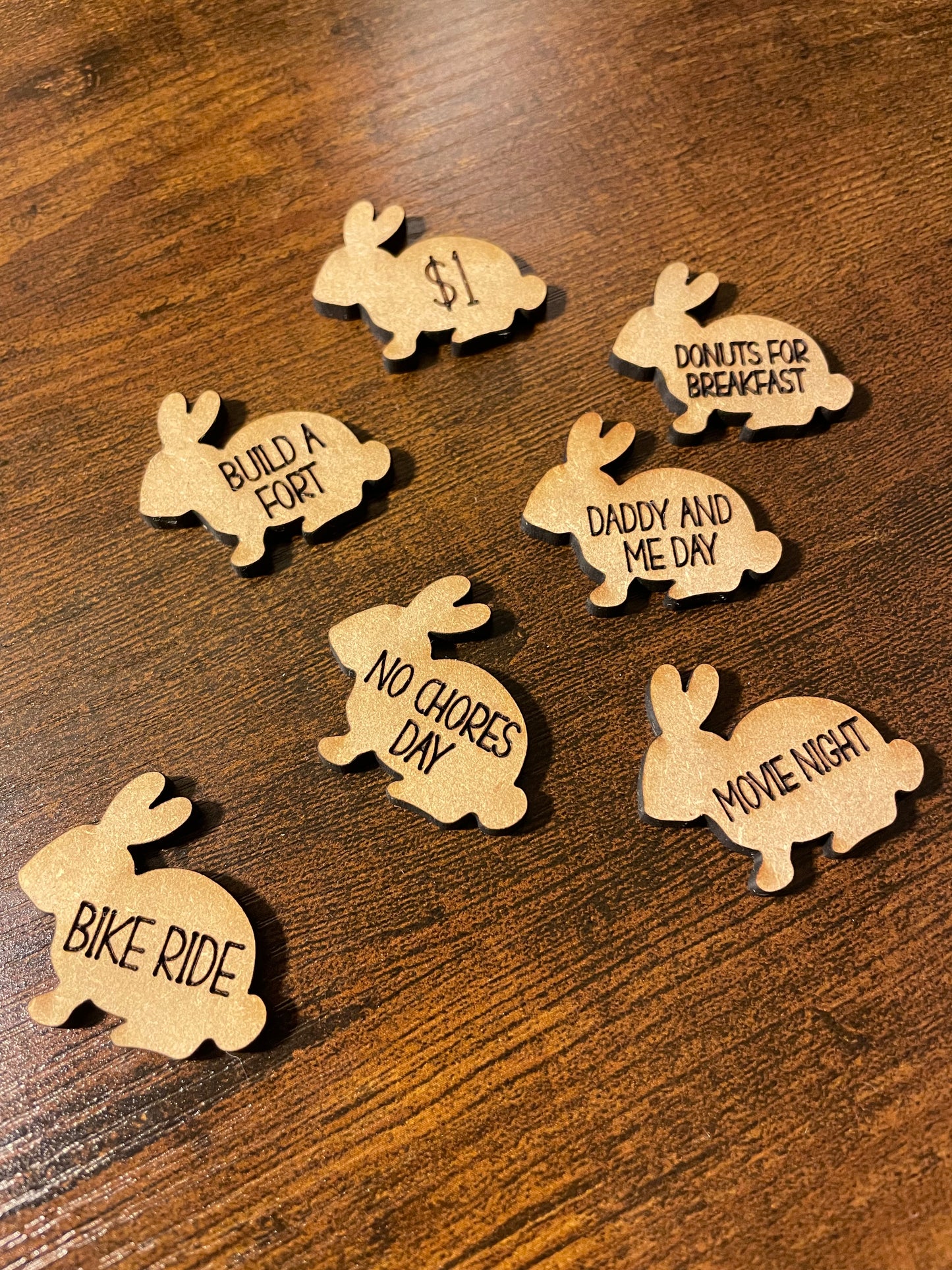 Wooden bunny-shaped token cutouts with engraved text on a wooden desk