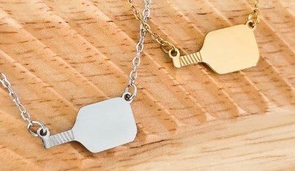 Two necklaces with paddle pendants on a wooden surface