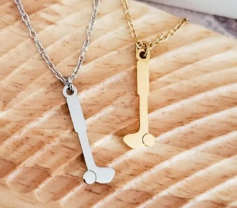 Two necklaces with golf club pendants both silver and gold plated on a textured beige surface